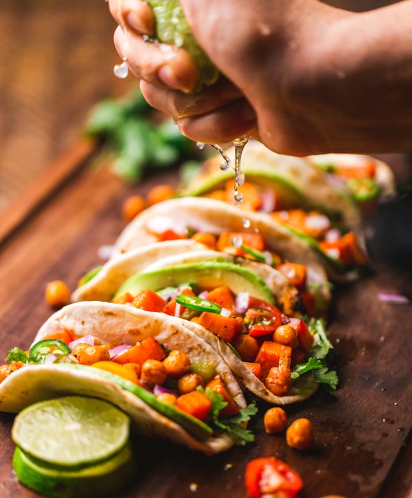 A platter of street tacos topped with fresh salsa, cilantro, and lime